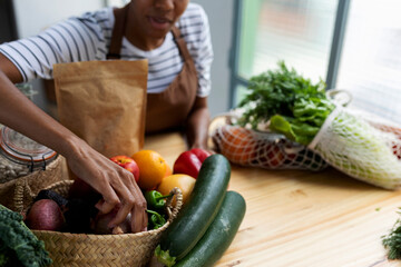 Woman with apron in kitchen , unpacking freshly bought organic fruit and vegetables