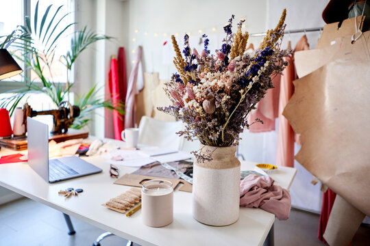 Flower in vase by candle on desk at design studio