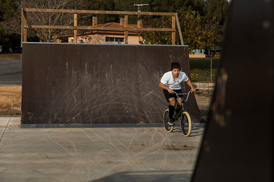Young man cycling by ramp at bike park