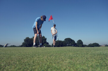 Friends playing golf against clear blue sky on course