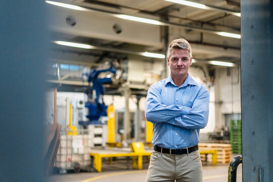 Confident manager with arms crossed standing in industry