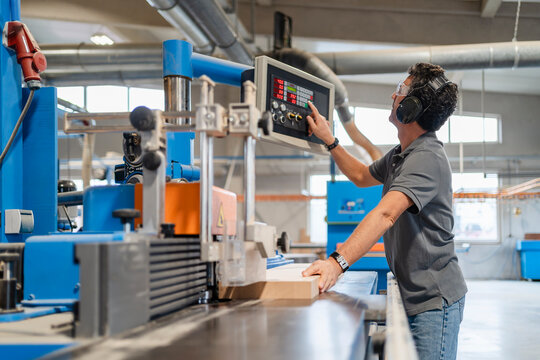 Carpenter operating control panel in production hall