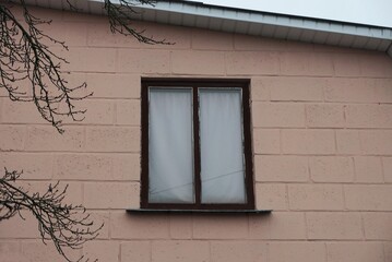 one window on the brown brick wall of the house in the street