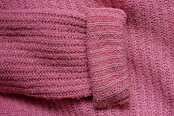 red fabric texture from a piece of crumpled wool sweater with a sleeve