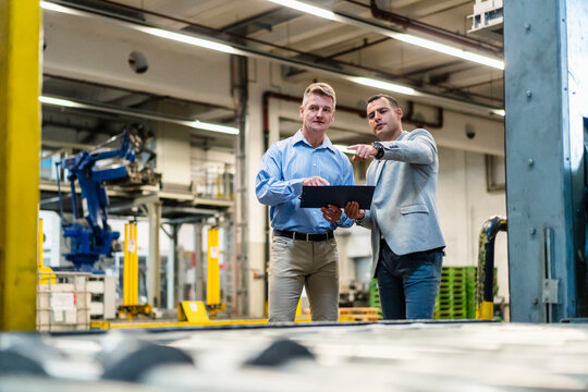 Mature male entrepreneur explaining plan to colleague while working in industry