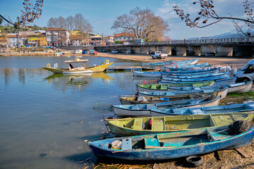 Fototapeta na wymiar Many colorful boats and canoes on the coast of Lake Uluabat and parking of cars near the lake. Bursa. Golyazi. Turkey. 22.01.2021.
