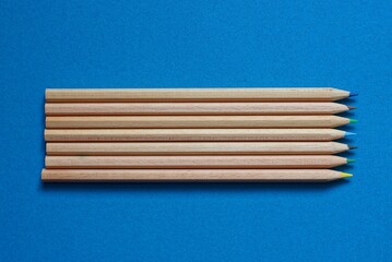 set of long brown wooden pencils lie on a blue table