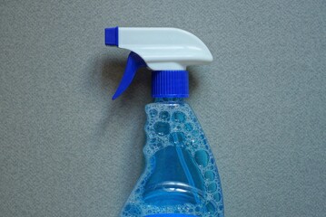 one plastic blue white spray bottle on a liquid bottle on a gray table