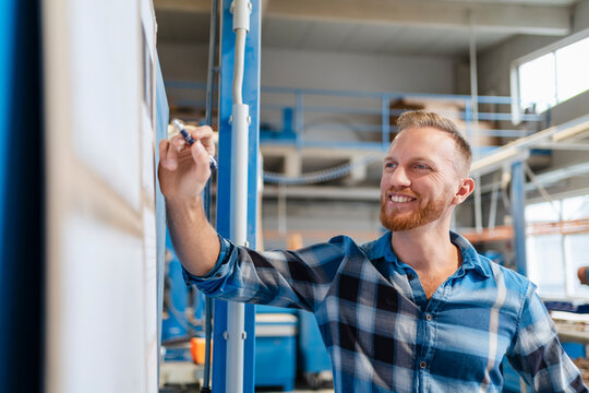 Portrait of carpenter smiling while checking plans hanging on board