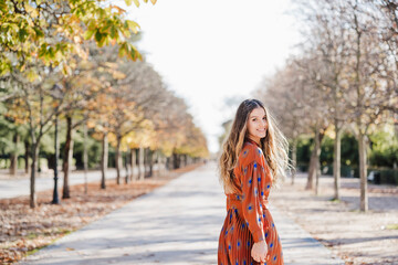 Cheerful fashionable woman walking on footpath during autumn