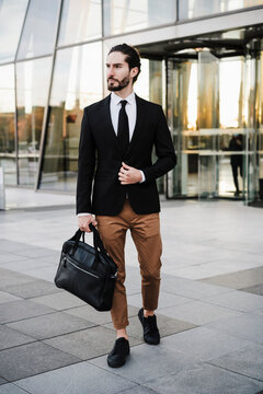 Businessman carrying briefcase while walking on footpath
