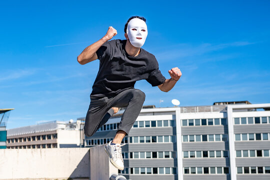 Young man wearing white mask running against sky