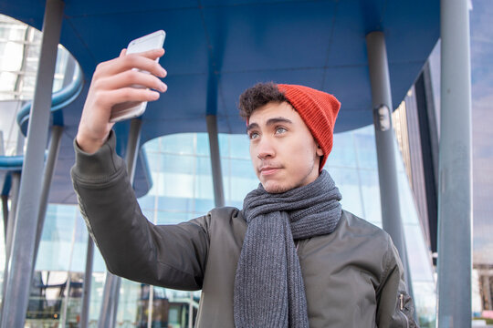 Young man wearing scarf taking selfie against modern building in city