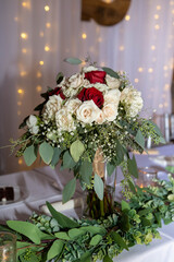 Red and white roses with bokeh lights in the background ; in a bouquet in a vase on the table