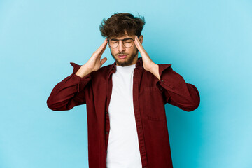 Young arab man on blue background touching temples and having headache.