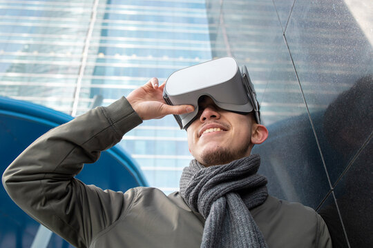 Smiling young man wearing virtual reality simulator by black wall
