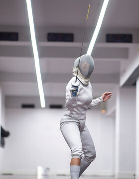 Woman&not;&dagger;in fencing outfit practicing at gym