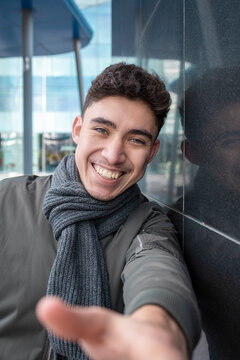Happy young man wearing scarf standing by black wall