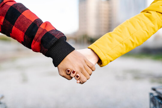 Young man and woman holding hands outdoors