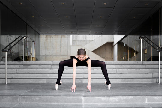 Ballerina in black leotard in modern concrete building