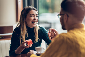 Surprised woman receiving gift box from boyfriend in a cafe