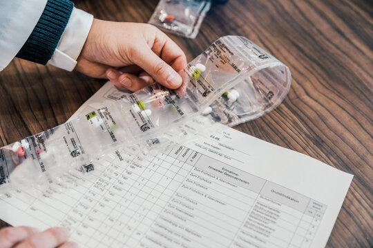 Hand of pharmacist with medicines and prescription in chemist shop