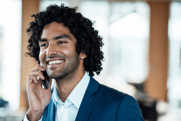 Cheerful male entrepreneur talking on mobile phone while looking away in office