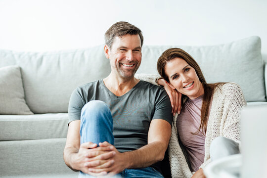 Smiling mature couple looking away in apartment