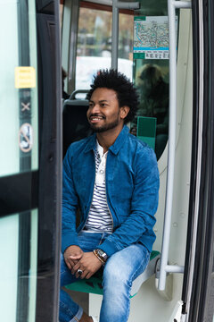 Stylish mid adult man with afro hair sitting in bus seen through doorway