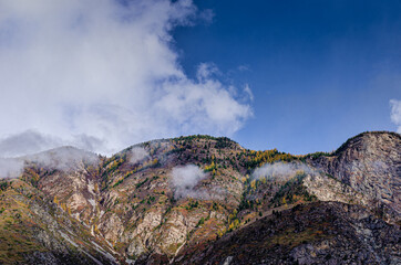 panoramic view of mountain summits between morning clouds on blue sky background