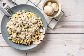 Tagliatelle Italian pasta with forest white champignon mushrooms creamy sauce and chicken or beef meat - homemade food in plate on the table top view close up copy space