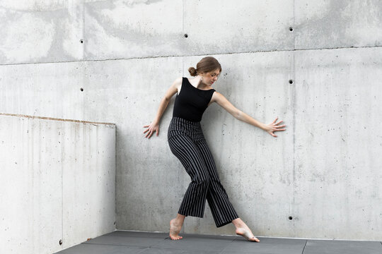 Dancer in black striped pants in front of concrete wall