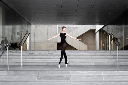 Ballerina in black leotard in modern concrete building