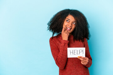 Young african american curly woman holding a help placard relaxed thinking about something looking at a copy space.