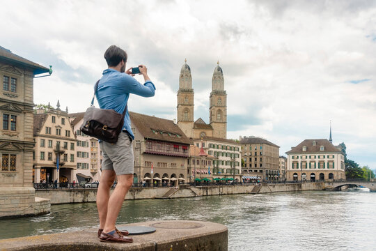 Young man taking image of the skyline of Zurich old town, Zurich, Switzerland