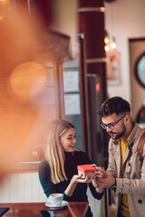 Young man surprising his beautiful girlfriend with a gift box