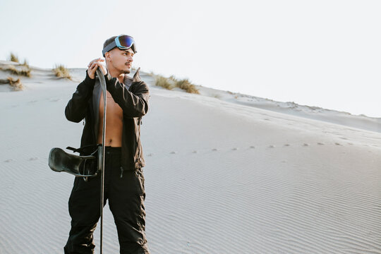 Handsome young man with sand board day dreaming while standing at Almeria, Tabernas desert, Spain