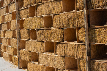 Hay bales are stacked in large stacks forming a wall