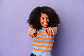 Young african american curly woman isolated on purple background cheerful smiles pointing to front.