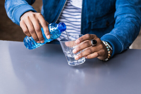 Close-up of mid adult man pouring water in glass on table at sidewalk cafe