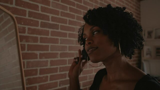 Beautiful african woman brushing her curls while looking at the mirror