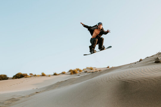 Young man performing stunt while standboarding at Almeria, Tabernas desert, Spain