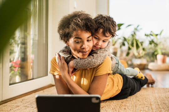 Mother and son using digital tablet while lying at home