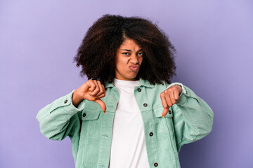 Young african american curly woman isolated on purple background showing thumb down and expressing...