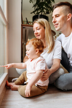 Happy Family With Baby Daughter Looking Through Window