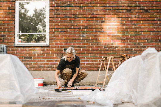 Woman crouching while renovating house during summer