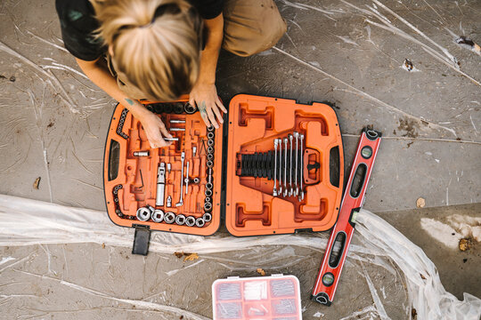 High angle view of woman with toolbox over concrete land