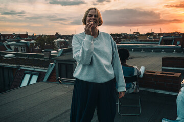 Portrait of smiling female with friends enjoying on building terrace during sunset