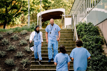 Smiling female and male colleagues with file moving down on staircase