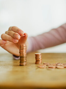 Woman's hand stacking coins, studio shot